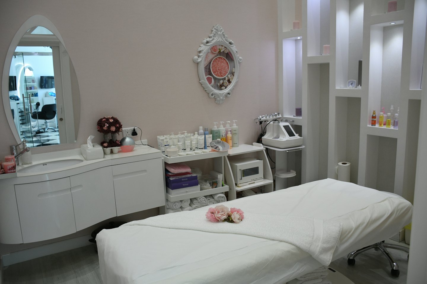 Schöner Behandlungsraum in einem Schönheitssalon mit weißem Bett und rosa Blumen.
