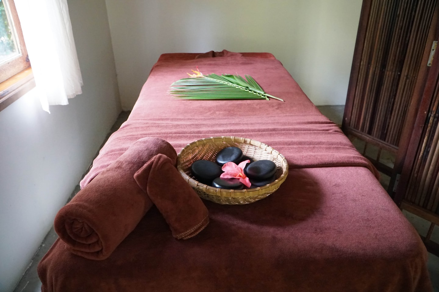 Massageliege mit Handtüchern und Steinen in einem Spa-Raum.