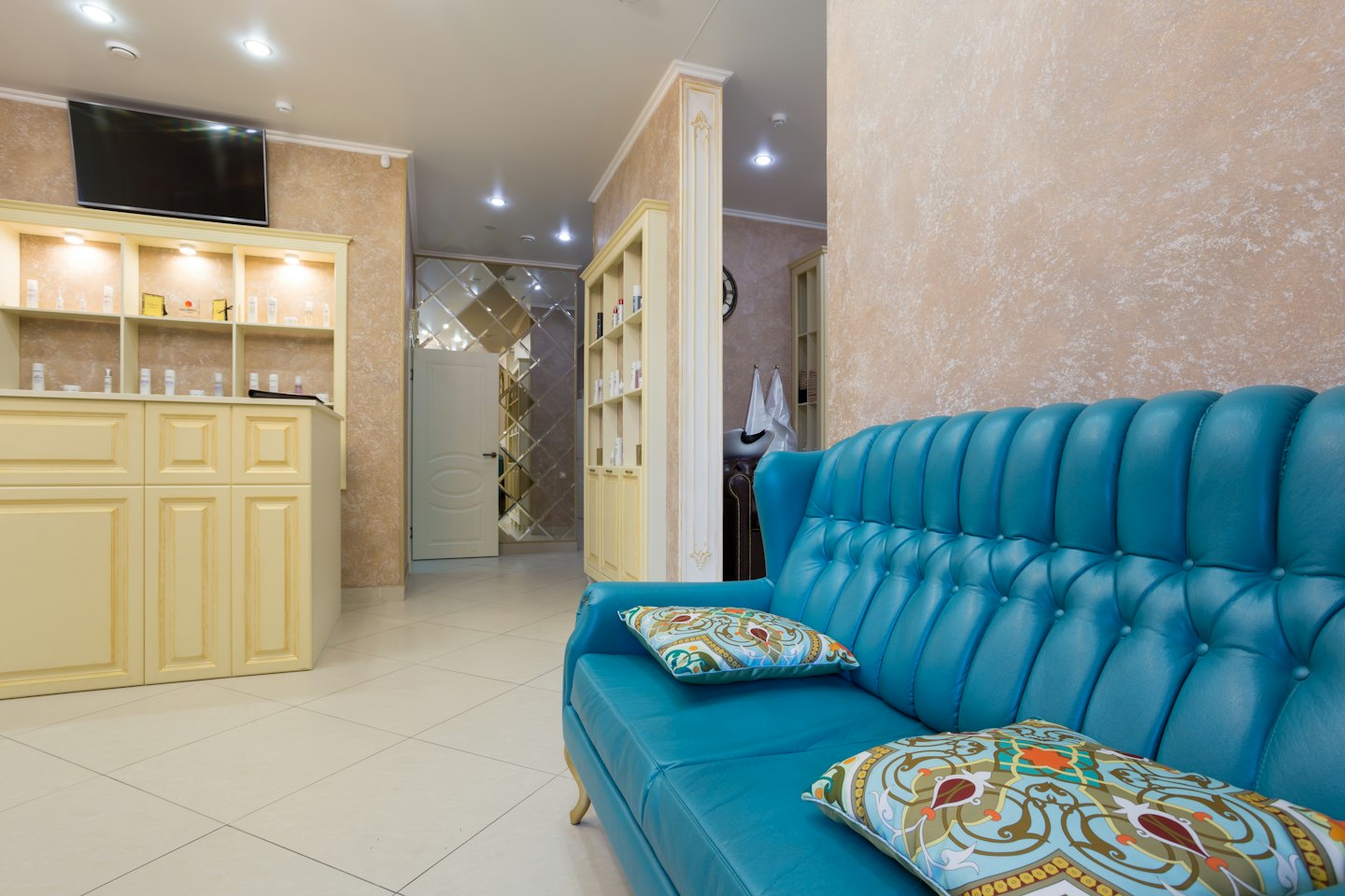 Türkiser Tufting-Sofa mit Zierkissen in einem Salon-Wartebereich.
