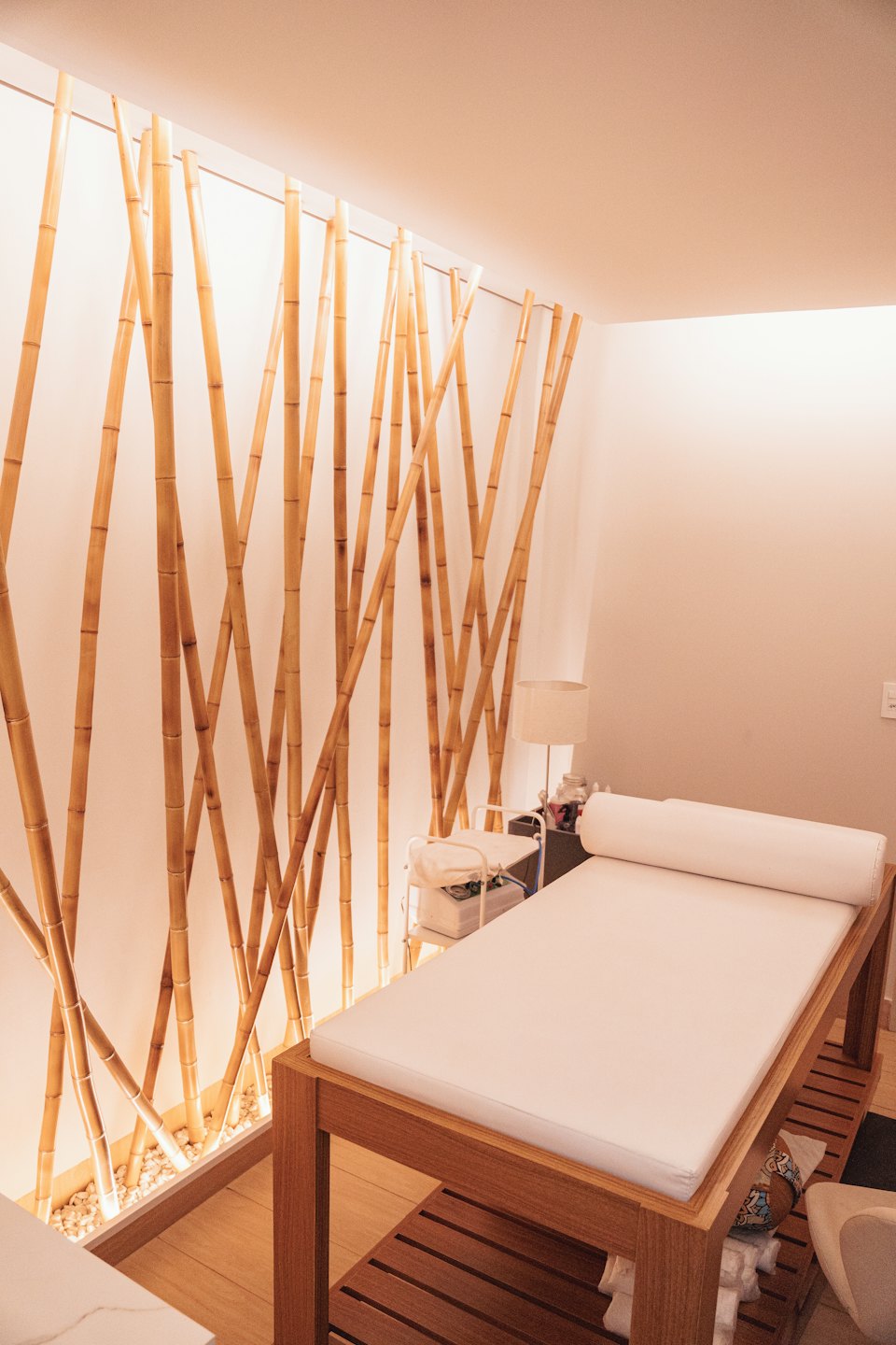 Leerer Spa-Raum mit Bambuswand und Massagetisch.