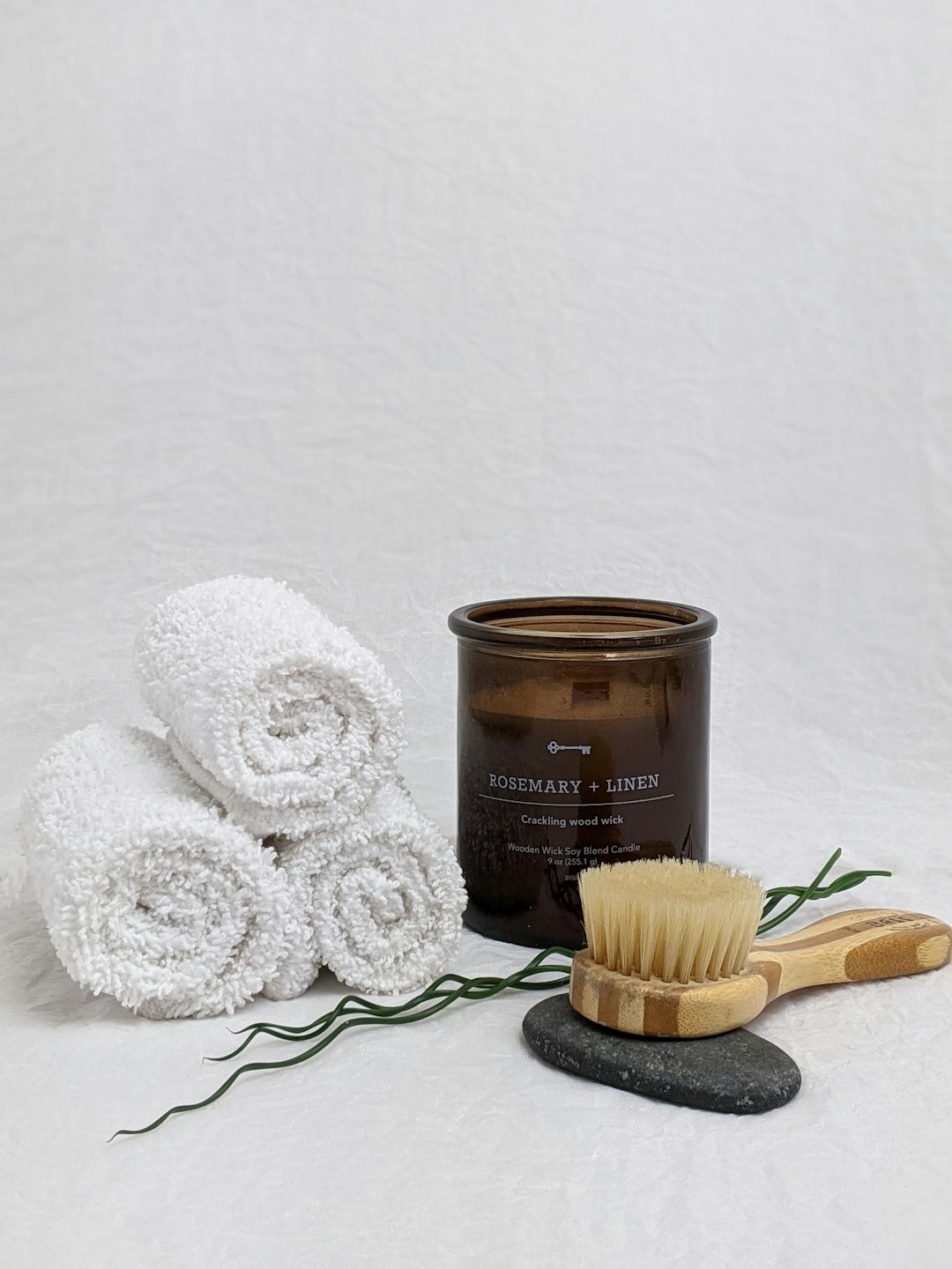 Spa products including towels, candle, and brush on a white surface.